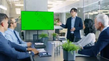 亚洲商人给他的业务同事报告/介绍, 指向绿色色度关键屏幕墙电视的结果.